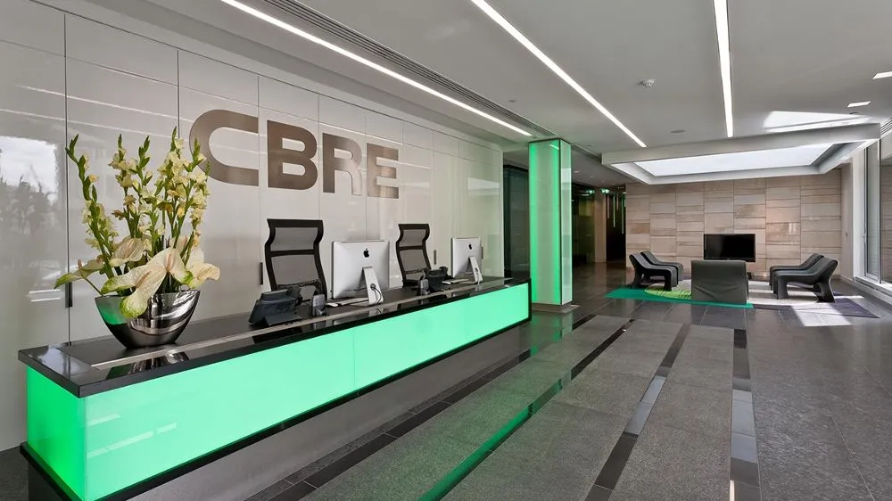 Modern CBRE office reception area with green illuminated front desk and seating lounge