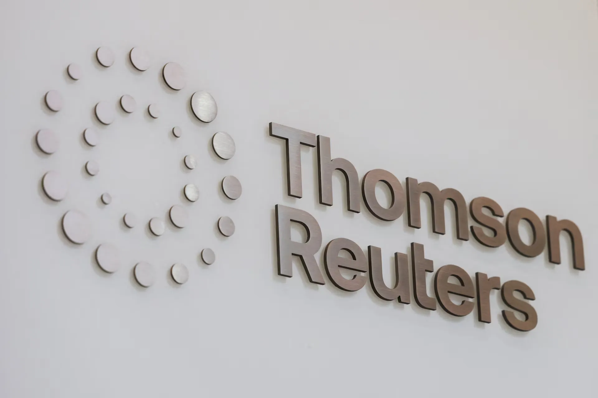 Thomson Reuters metallic logo mounted on a white office wall